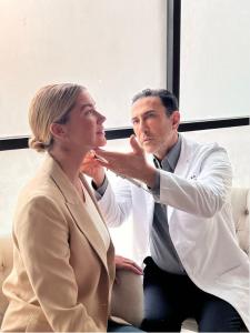 Dr. Simon Ourian is shown performing a cosmetic treatment on a smiling female patient seated in a white chair, highlighting his skill in non-surgical aesthetic procedures.