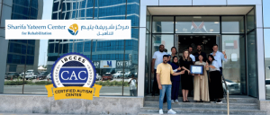Image of Sharifa Yateem Center for Rehabilitation staff and management holding their Certified Autism Center™ certification outside the center's entrance.