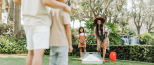 A family enjoys a game of cornhole in their backyard on a sunny day.