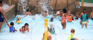 Children having fun in a water park, splashing and laughing under colorful water slides.