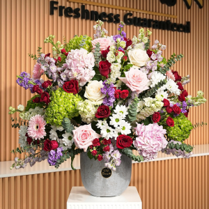 A mixed flower arrangement in a grey ceramic vase