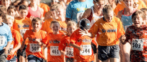 Children in orange shirts running together in a marathon.