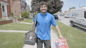 J. Blanton Plumbing technician smiling and carrying a toolbox and cleaning supplies, representing the company's dedication to plumbing services, repairs, and maintenance.