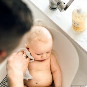 Infant getting a bath by mother with a washcloth