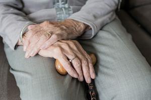 Hands of elderly woman on walking stick