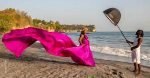 St Lucia Flying Dress Photo Shoot on a St Lucia beach with Photo Assistant holding up an off camera light