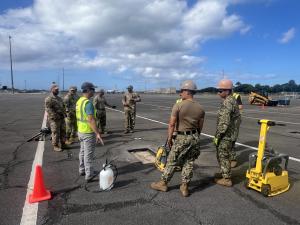 Warfighters standing on airfield next to test patch for Trident Warrior