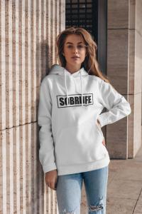 A woman wearing a SOBRLIFE sweatshirt stands and poses for a pic