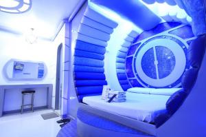  Astrotel's space-themed room with blue padded walls, a circular bed, futuristic decor, and ambient blue lighting.