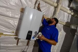 J. Blanton Plumbing technician fixing a water heater, showcasing their $49 water heater flush and maintenance program. The image emphasizes the importance of water heater maintenance and the company's expertise in all their services.