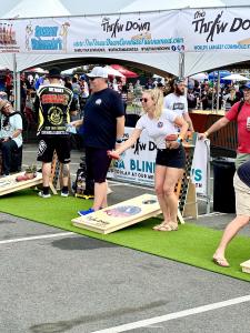 Male player in black t-shirt and female player in white t-shirt competing at the Throw Down Cornhole Festival