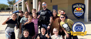 Children happily posing for a photograph with a Surprise PD police officer, showcasing community engagement and friendship.