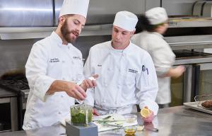 Chef instructor teaching student to make sauce