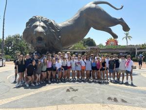 The 2024 tour group standing in front of the big lion statue at the San Diego Zoo