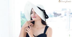 A woman wearing a white sunhat and black dress showcases a collection of colored gemstone engagement rings, highlighting the elegance of non-traditional engagement rings.