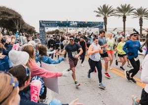 Runner crossing the starting line at the SEASIDE SCHOOL™ Half Marathon and 5K in Seaside, Florida on 30A.