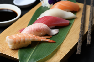 A beautifully presented platter of assorted sushi nigiri featuring fresh shrimp, tuna, salmon, and white fish, served on a bamboo leaf with chopsticks on the side at Sushi Song, a top sushi restaurant in South Florida.