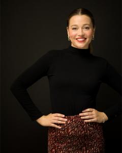 This photo shows Madhouse Dance founder Olivia Kingston smiling against a black background.