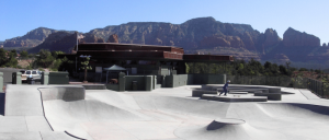 A lively skateboard park filled with skaters showcasing their skills on various ramps and obstacles in a sunny environment.