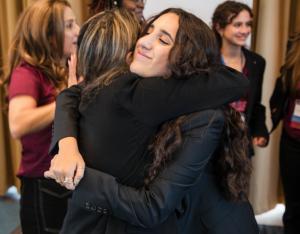 Youth leader Mahsa Riar hugs another participant at the Girl emPower Summit