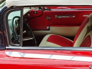 Close-up of a sleek, red exotic car showcasing its side and wheel.