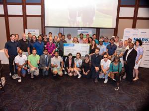 A group photo of participants smiling and posing together in a conference room setting from the 2024 Markham Board of Trade Corporate Charity Golf Classic, sponsored by Kylemore. They are holding a large ceremonial cheque for $4,000 made out to Evergreen 