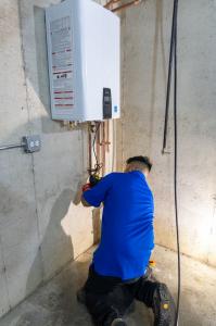 J. Blanton Plumbing technician repairing a water heater, highlighting the company's expertise in hot water heater repair, water heater maintenance, and 24-hour plumbing services as part of their partnership with the Edgebrook Sauganash Chamber of Commerce