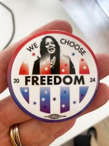 A round pin imprinted with "We Choose Freedom" and a photo of Kamala Harris.