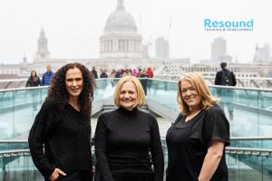 three people dressed in black standing in city with gray skys