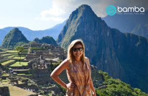 A happy tourist standing in front of Machu Picchu in Peru