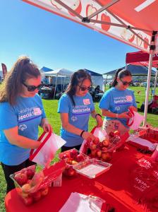 Rockit™ Apple and Special Olympics working together (photo shows three people in Special Olympics shirts packing Rockit Apples into bags to give away at Special Olympics event.