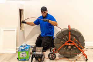 J. Blanton Plumbing technician performing a camera sewer inspection, emphasizing the company's No Drip Club, 24-hour plumbing service, and camera sewer inspections as part of their involvement in the Arlington Heights Chamber of Commerce.