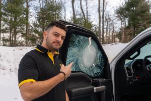 Cameron Khoroushi, Director of Design & Engineering at Alpine Armoring, stands next to the MASTIFF® window shot with a round from a .50 caliber rifle.