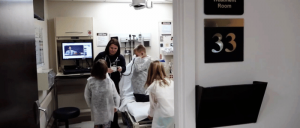 A hospital staff with three children wearing white lab coats at hospital room.