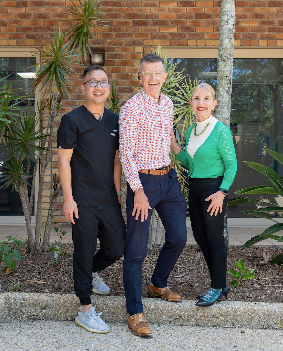 Group photo of Medland Orthodontics Orthodontists, from left to right, Dr William (Will) Luong, Dr William (Bill) Medland, and Dr Patty Medland, standing in front of the Benowa Practice, located on the Gold Coast