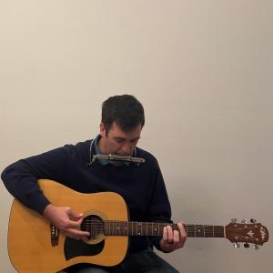 Joe Stevens playing guitar and harmonica