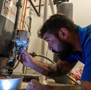 J. Blanton Plumbing technician repairing a water heater, highlighting the No Drip Club's Free Annual Home Winterization service, Chicago water heater installation, and water heater repair expertise.