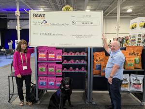 RAWZ Natural Pet Food owners, Janet and Jim Scott, pose with a dog from National Service Dogs as they present a $50,000 check at the Pets Canada Industry Show in Toronto.