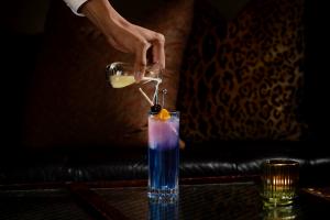 Server pouring into purple cocktail at club room new york