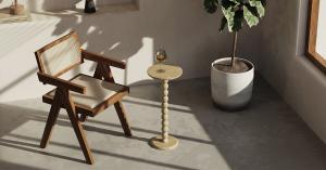 A modern space with an OIXDESIGN Travertine Cocktail Table holding a glass of wine, paired with a wooden chair and a potted plant, highlighting its minimalistic and elegant design.