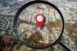 Neighborhood from the air with magnifying glass and red locator symbol - real estate concept