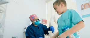 A young boy sits in a dental chair while a dentist cleans his teeth, ensuring a bright and healthy smile.