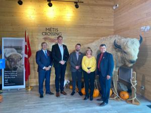 Five people standing in front of stuffed bison in front of wooden wall