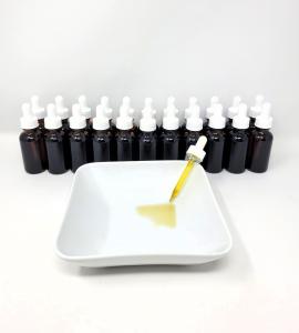 a row of amber bottles with a plate with one dropper spilling liquid into the plate