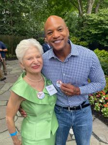 Two people at a garden reception, showing round metal buttons.