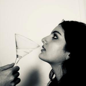 Adeline looks in profile at a masculine hand offering her a drink from a martini glass