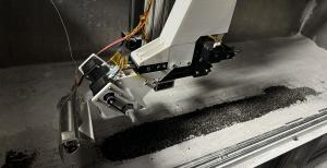 Robotic apparatus developed by SpaceFactory deposits lunar asphalt made from regolith and biopolymers onto a bed of lunar soil simulant, demonstrating advanced construction techniques for lunar infrastructure.