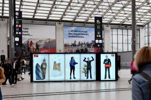 Photo depicting Hologrid by Holoconnects - five large, 7-foot tall hologram boxes featuring immersive, life-size 3D hologram content for a Visit Britain advertising campaign on display at Gare du Nord train station in Paris, France