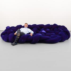 A businessman reclining on a large purple sofa