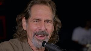 Marlon Hoffman, a man with brown hair and a gray beard, sings into a microphone